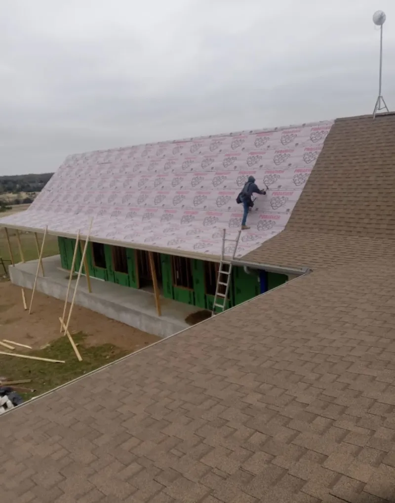 Worker preparing underlayment for a metal roof installation in Peoria